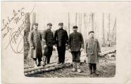 Cinq officiers mariniers en uniforme dans une forêt.