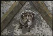 1 vue Aincourt. - Chapelle Saint-Sauveur : représentation de la tête du Christ sculptée sur un mur.